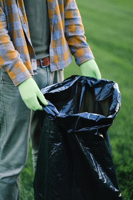 In the foreground, three large blue trash bags made of plastic with a slightly glossy finish and visible creases are positioned on the pavement, leaning against the rear side of a white commercial van